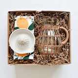 Rattan pitcher paired with a Hazelmade tea towel and handmade ceramic juicer from She Made.