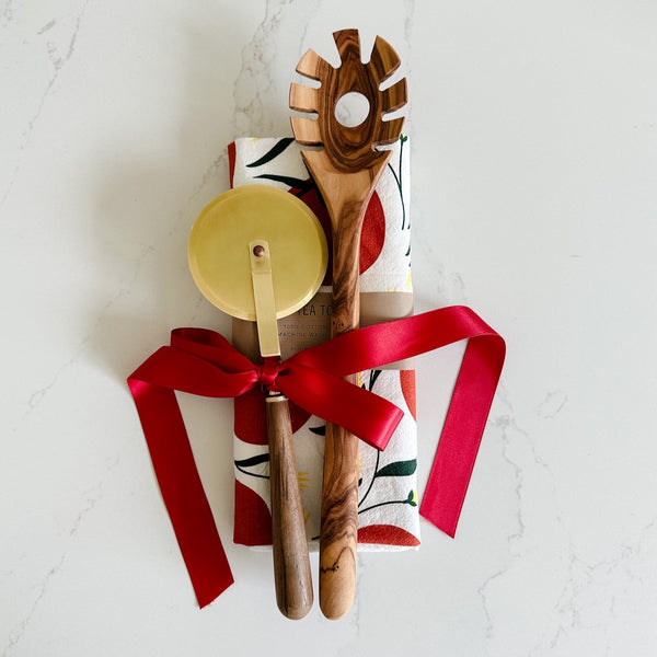 A cute host gift, a gold and wood pizza cutter, olive wood pasta spoon and tomato tea towel.