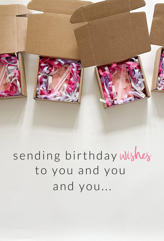Four gift boxes filled with colorful shredded tissue paper, a candy bar, lip balm, and a wish sparkler. At the bottom is the message sending birthday wishes to you and you and you.