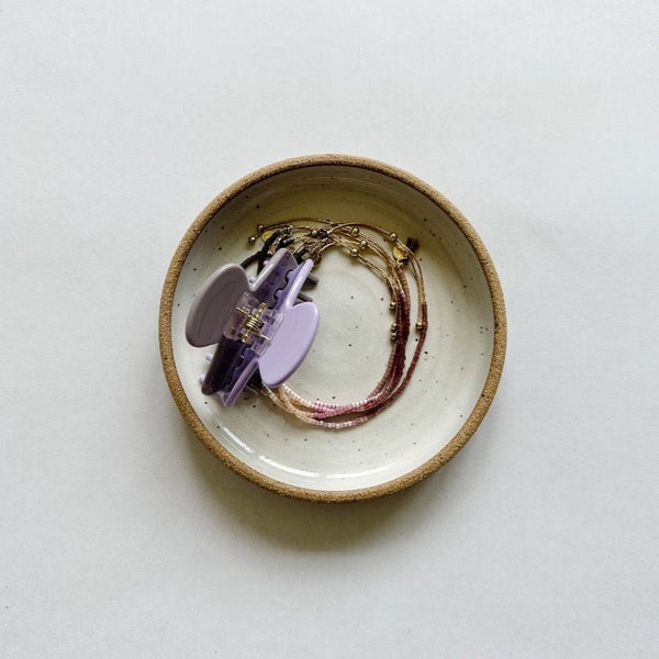 Small m.bueno dish featuring a lavender hair claw and shashi jewelry. 