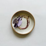Small m.bueno dish featuring a lavender hair claw and shashi jewelry. 