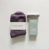 The coziest cloud socks in plum from Le Bon Shoppe, Thulisa Naturals Lavender Geranium shower steamers, and Solana lip balm.