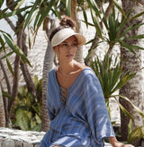 A woman wearing a blue dress and a Bali Harvest Straw Sun Visor.