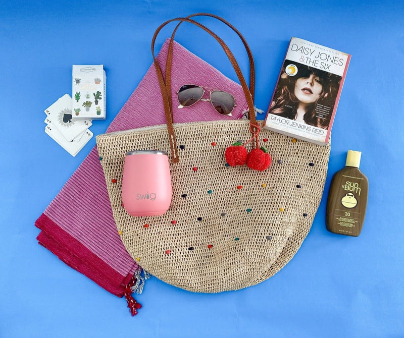 Mar y Sol tote paired with playing cards, Daisy Jones book, pink towel and sun acessories.