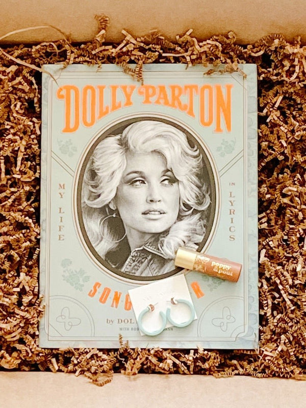 Dolly Parton book paired with lip tint from Poppy & Pout and Sol Earrings from Nat and Noor.