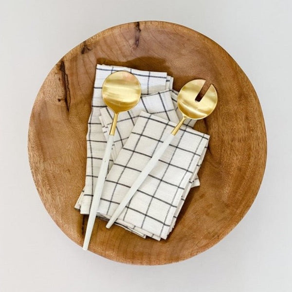 Beautiful wood bowl with white and gold serving set and grid napkins.