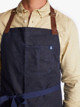 Navy waxed apron with brown leather straps.