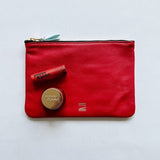 Red Certain Standard 50/50 pouch with blood orange poppy and pout lip balm and lip scrub.