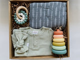 Mebie baby gown and bow paired with muslin swaddle blanket, rainbow stackers and a teether for the sweetest baby gift.