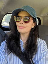 Woman wearing the Nura hoops with baseball hat and button down shirt.  These earrings are  perfect worn alone or stacked.