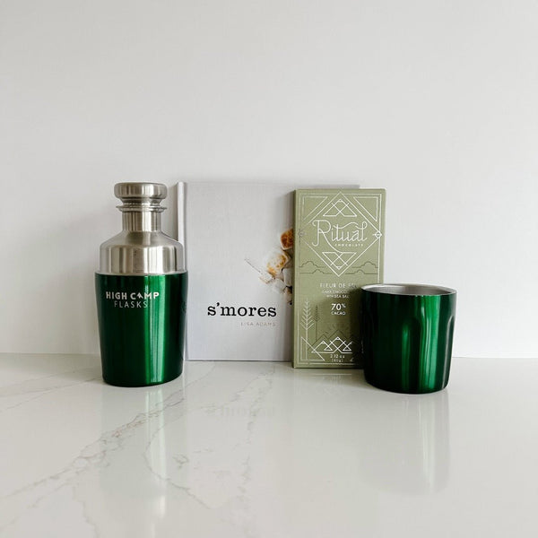 The perfect gift for the camping friend includes this Kelly green flask from High Camp, a S’mores book of recipes, and a chocolate bar from Ritual Chocolate.