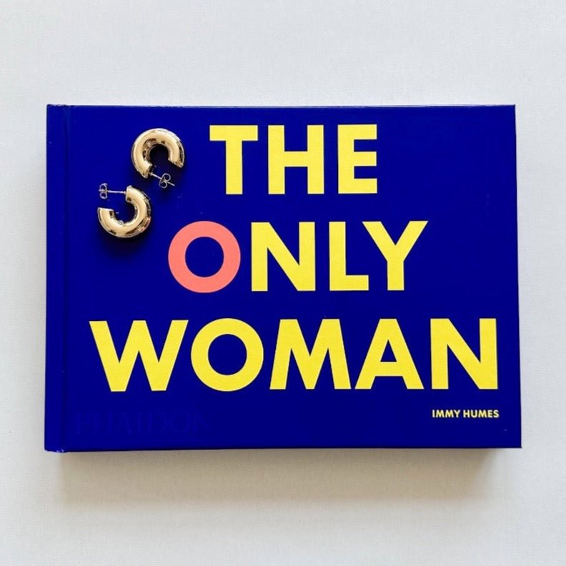 The Only Woman book and gold hoop earrings sitting atop it.