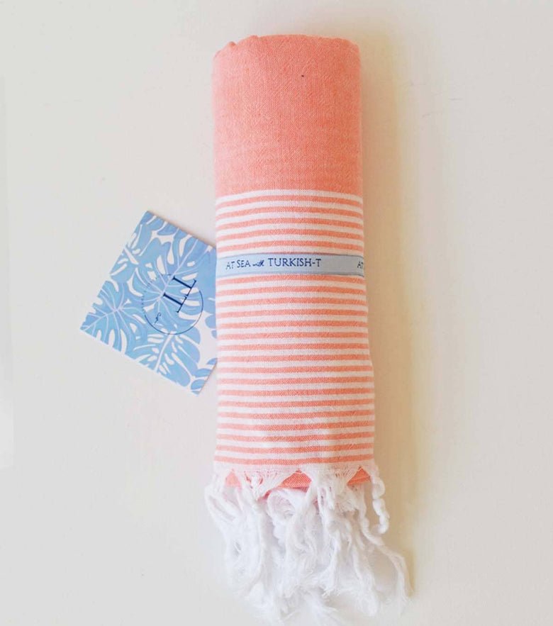 A coral colored striped Turkish towel that’s perfect for the pool or the beach.