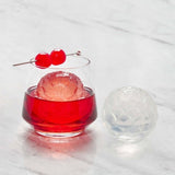 A round ice cube from a petal ice tray in a cocktail.