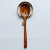 Handmade spoon rest paired with a pretty wood strainer spoon.