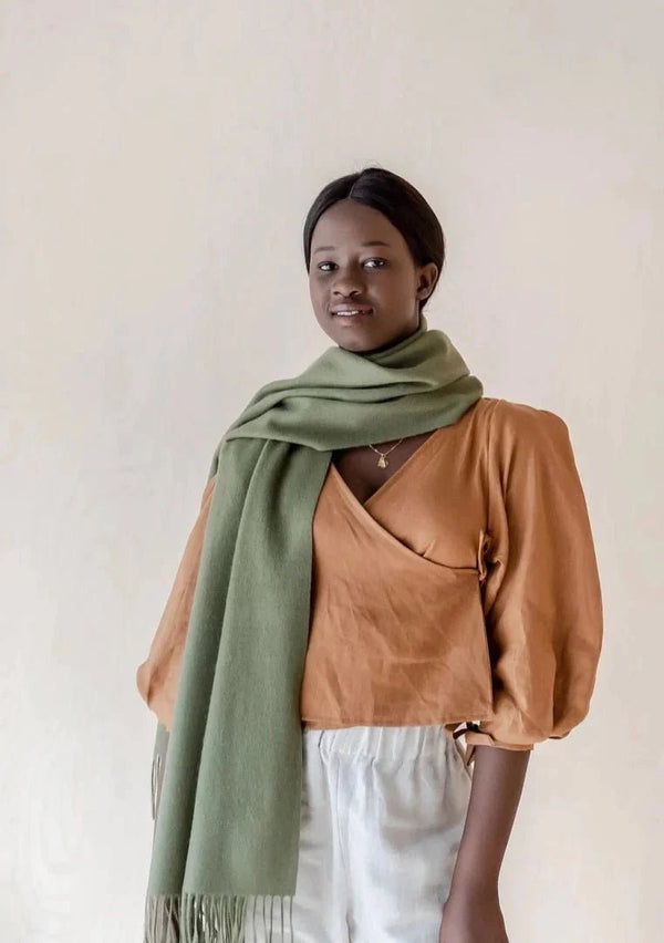 Lambswool Oversized scarf in Olive color beautifully draped around shoulders of a woman.