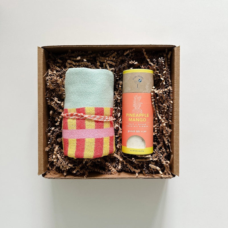 A fun gift box with Kraft crinkle filled with one Blue Henry Pineapple Mango salt + sugar and a Turkish hand towel from Slate in a cheerful combination of red, yellow, cyan and pink.